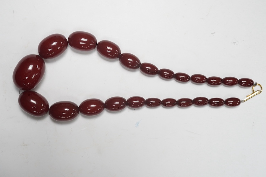 A single strand graduated oval simulated cherry amber necklace, 38cm, gross weight 47 grams. Condition - fair to good